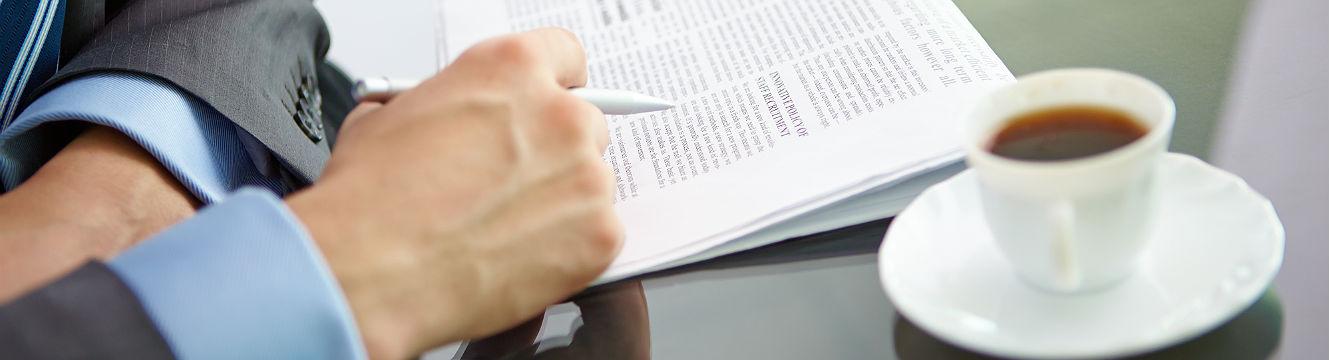 Un homme lit le journal en buvant un café